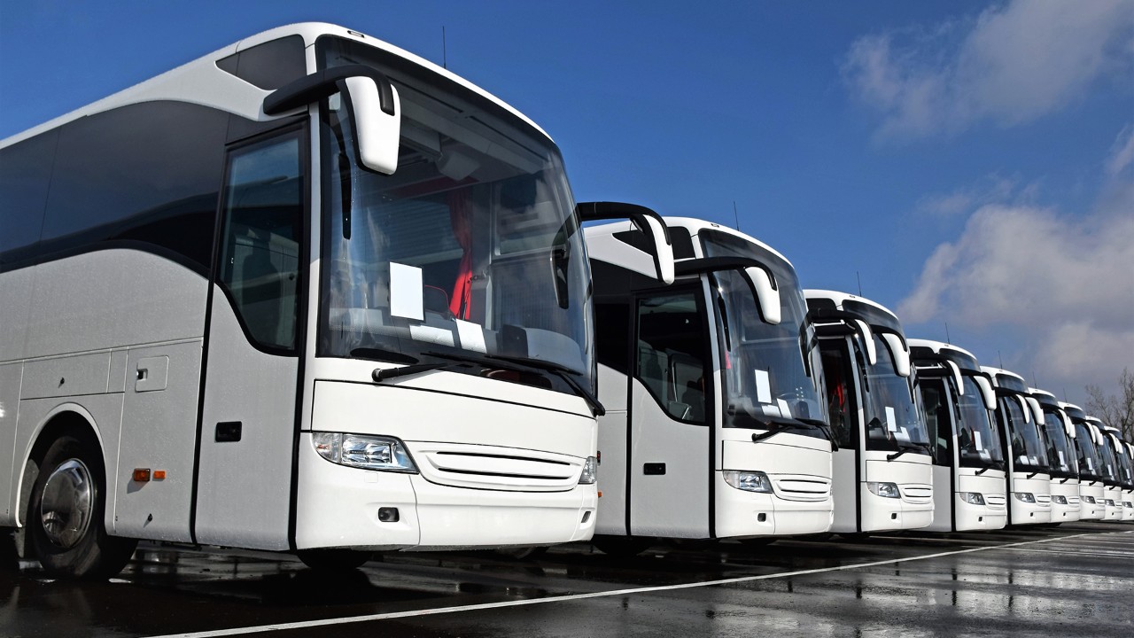 Front right side shot on the white tourist buses in a row on the parking.